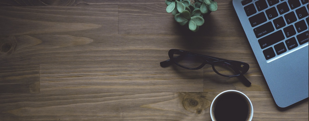 Ein Kaffee und eine Brille neben einem PC